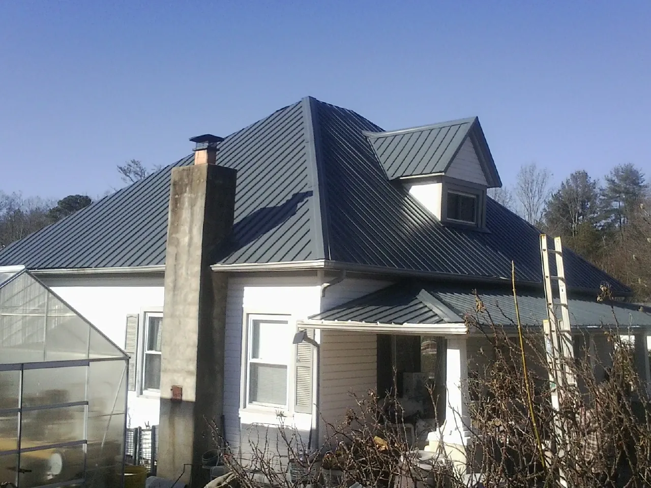 Dark blue standing seam metal roof on a white farmhouse with dormer — Slate & Tile Roof Repair by Roofing Brothers in Newton Lower Falls