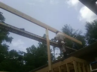 Carpenter setting a ridge beam over a new addition frame — Ice Dam Removal by Roofing Brothers in Newton Lower Falls