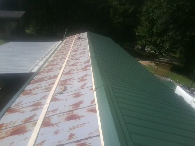 Old rusted panels beside newly installed green metal roofing — Wind Damage Roof Repair by Roofing Brothers in Newton Lower Falls