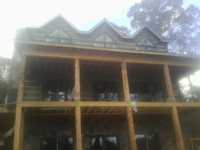 Dormers and porch framing on a large log home under construction — Roof Coating work by our crew in Newton Lower Falls