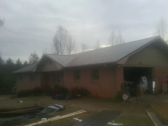 Gray metal roof on a stucco house with an attached garage in Newton Lower Falls
