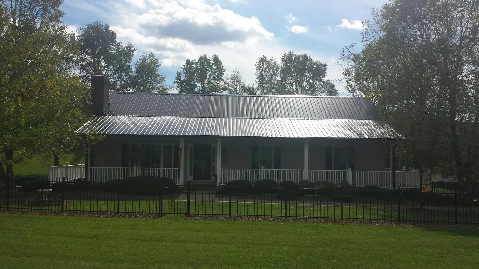 Gray metal roof on a brick ranch with a full width front porch — Gutter Guard Installation work by our crew in Newton Lower Falls
