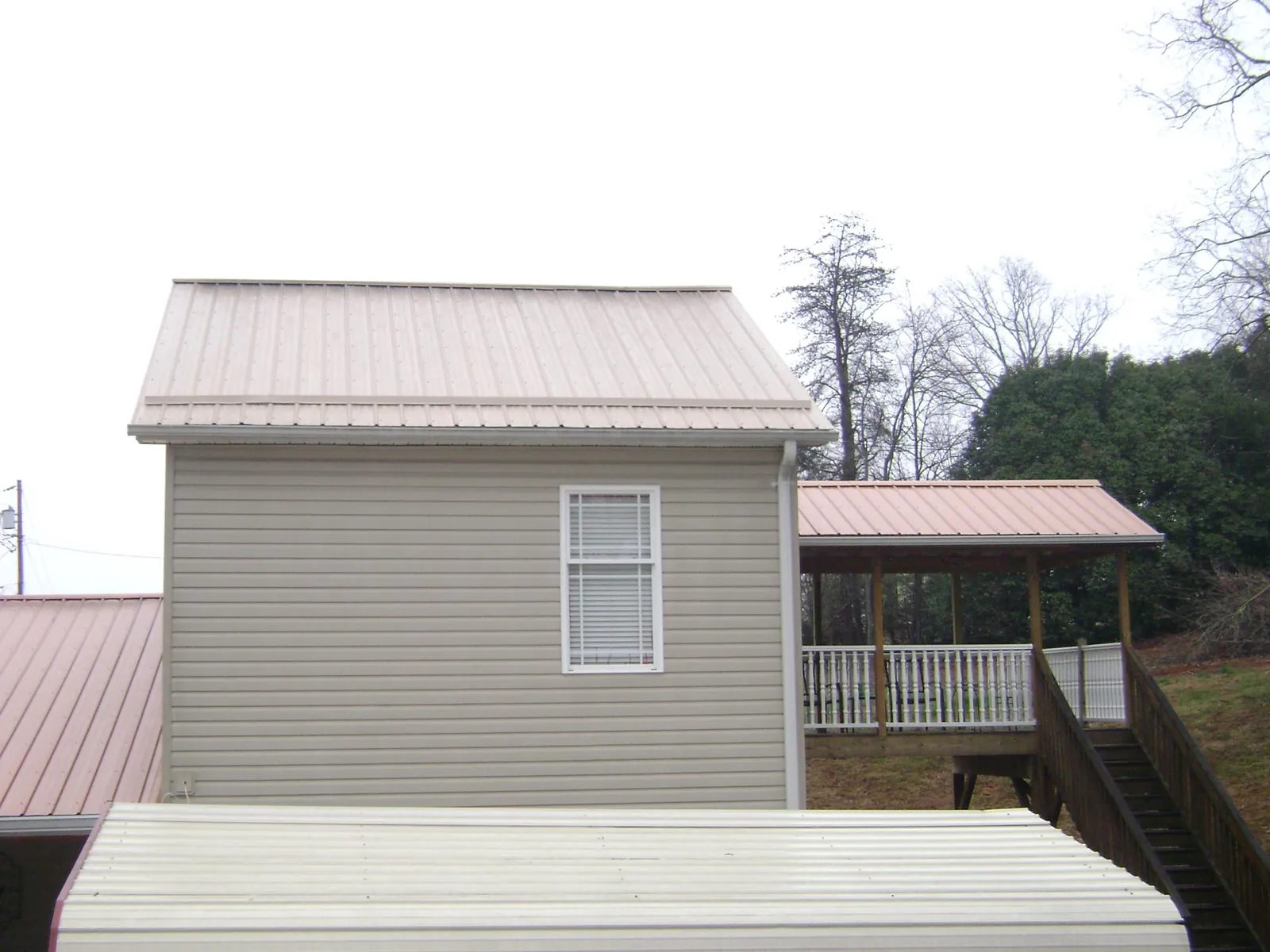 Tan metal roofs on a two story addition and attached porch, from a Roof Replacement job in Newton Lower Falls