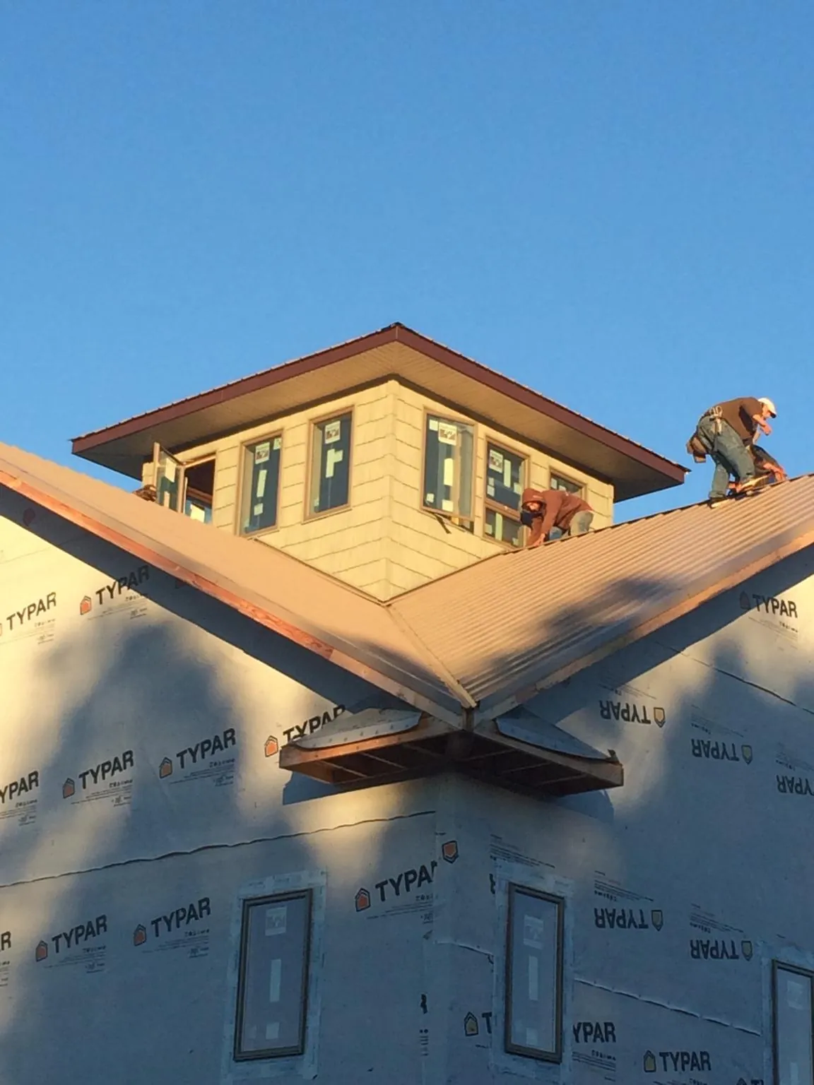Roofers working around a rooftop cupola on a new metal roof at sunset — Roof Waterproofing in Newton Lower Falls by Roofing Brothers